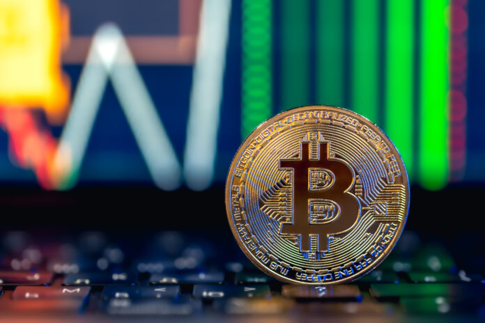 Golden Bitcoin coin on keyboard. Stock market trading chart online candlestick.